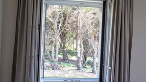 A window with curtains, a view of trees, and a radiator below. - Villa mit großem Grundstück direkt am Mer by Interhome (Concarneau)