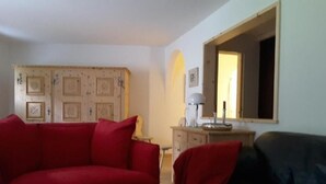 Una sala de estar con dos sofás, una mesita y un mueble.