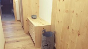 Un pasillo de madera con un banco de madera y un bote de basura metálico.