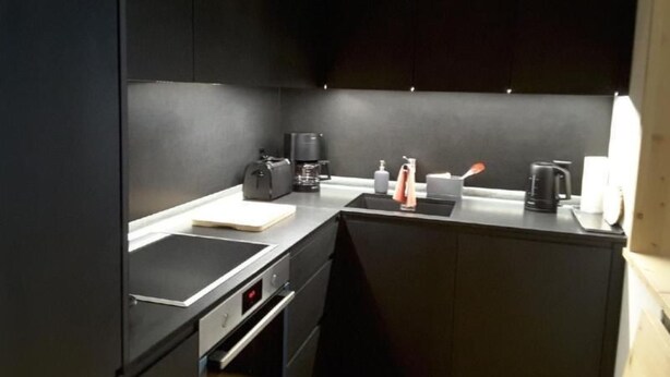 Una cocina compacta con horno integrado, cafetera y lavaplatos.