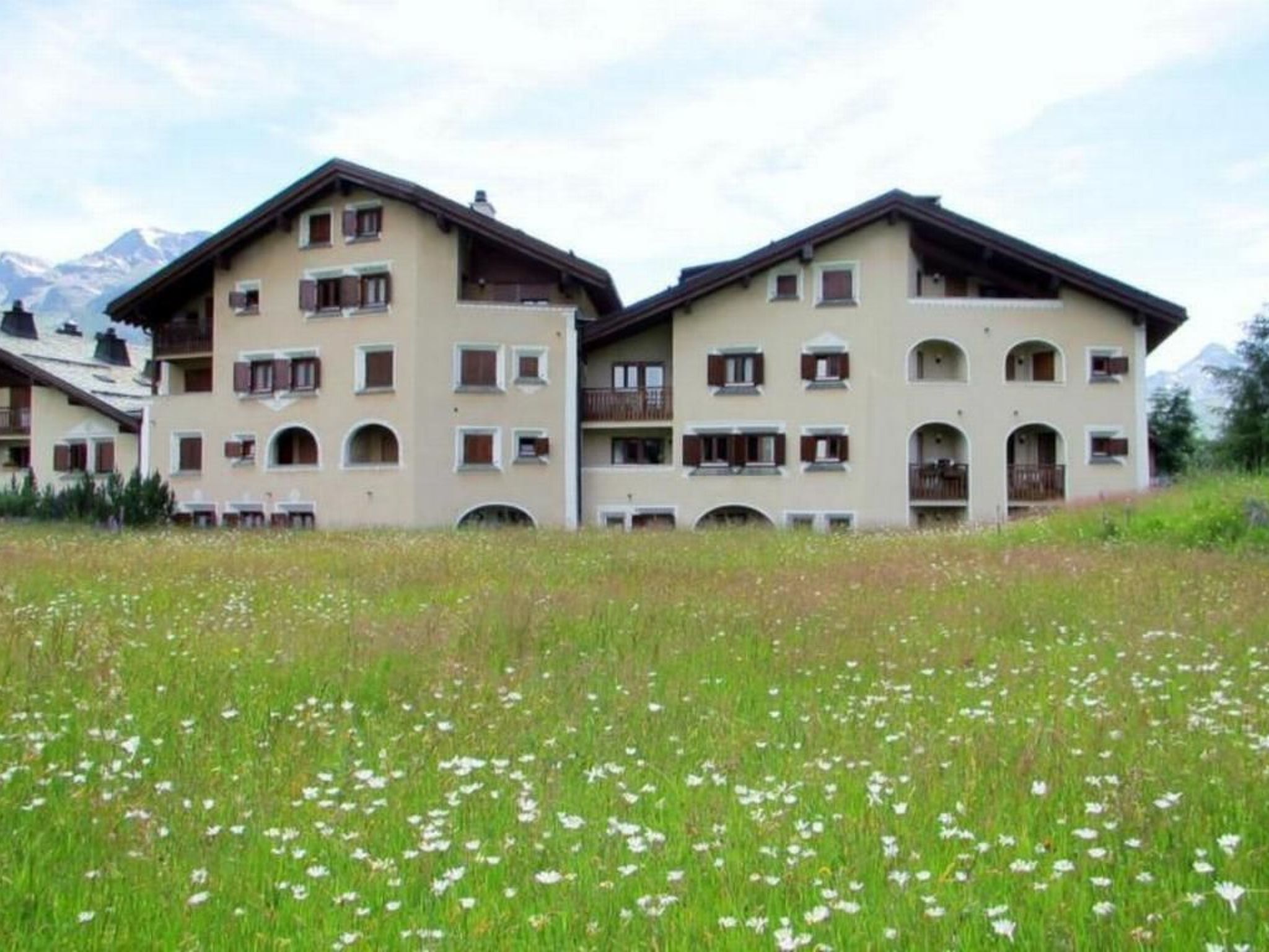 Un hôtel à plusieurs étages, doté de balcons, situé dans un cadre montagneux.
