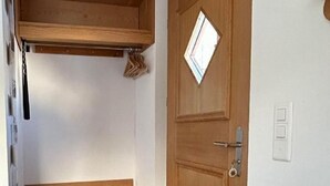 Ein Flur mit einer hölzernen Bank, einer Tür mit Fenster und einem kleinen Regal darüber.