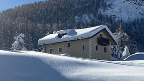 Ein schneebedeckter Berg mit einem Chalet im Vordergrund.