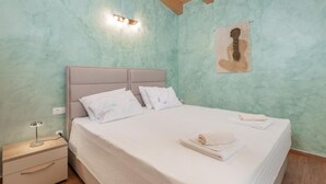 A bedroom with a bed, a nightstand, a wall-mounted light, and a framed picture. - Villa Violette mit Pool nahe Stadtzentrum by Interhome (Drenje)