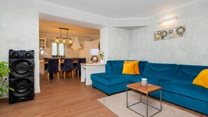 A modern living room with a blue sofa, a coffee table, and a kitchen visible in the background. - Villa Violette mit Pool nahe Stadtzentrum by Interhome (Drenje)