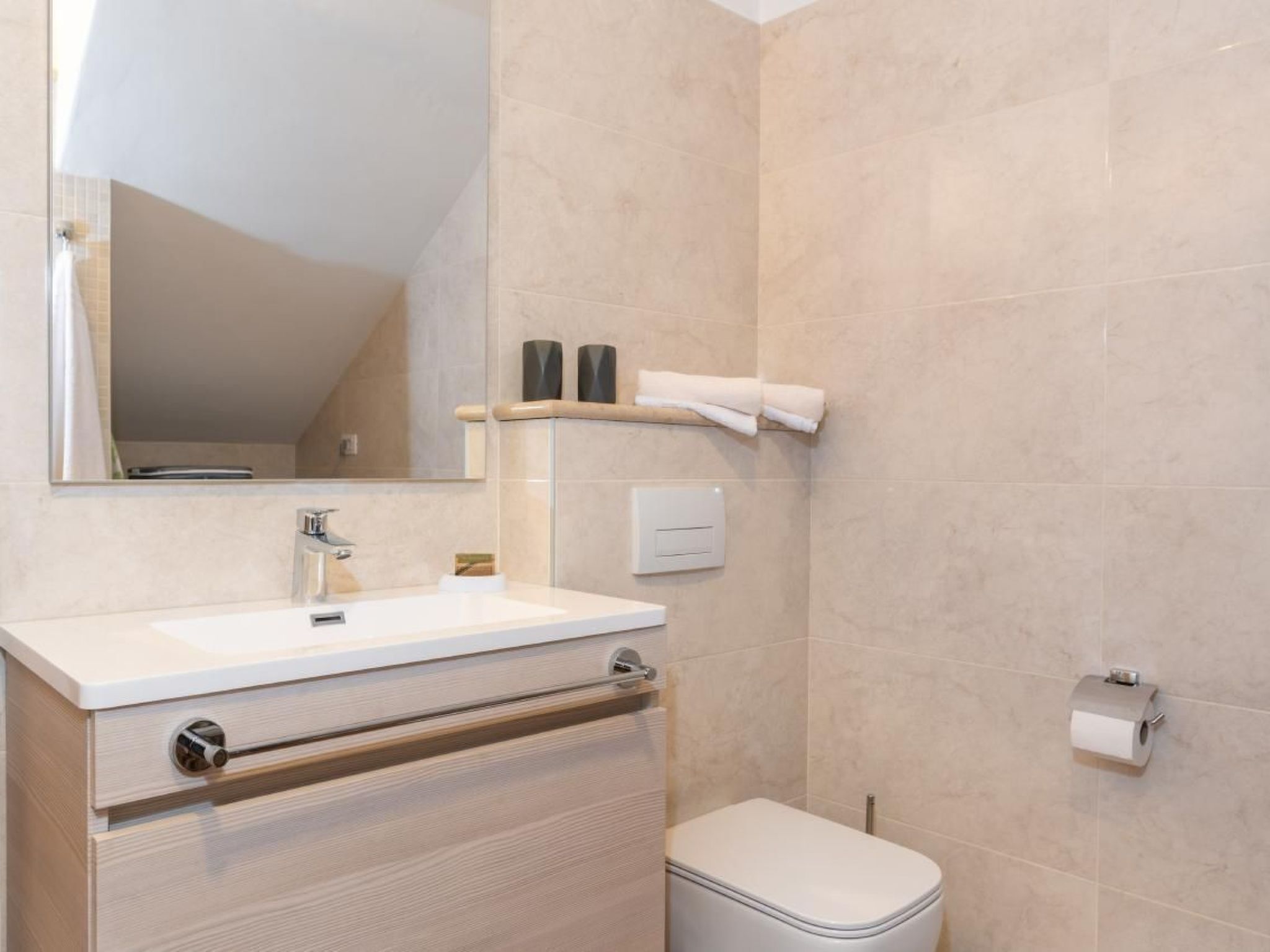 A bathroom with a white sink, a mirror, a toilet, and a towel rack.