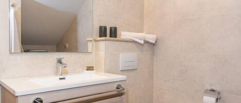 A bathroom with a white sink, a mirror, a toilet, and a towel rack.