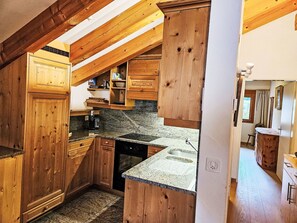 Une cuisine avec des armoires en bois, des comptoirs en granit et un four encastré.