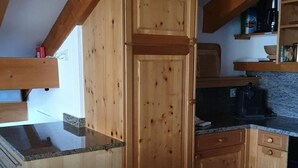 A kitchen with wooden cabinets, granite countertops, and a built-in oven. - Chesa Foppas Nr. 7 by Interhome (Sils Maria)