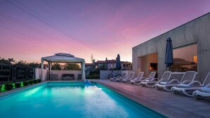 Une piscine avec des chaises longues et un espace salon abrité.