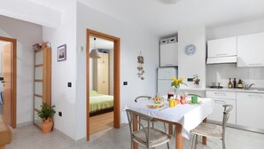 Une cuisine moderne avec des meubles blancs, une table à manger pour quatre personnes et un petit coin repas avec des chaises.
