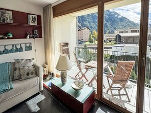 Ein Wohnzimmer mit einer Couch, einem Couchtisch und Blick auf einen Balkon mit Stühlen.