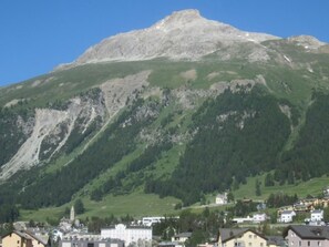 A mountain with a small town at its base, featuring a mix of residential and commercial buildings. - La Residenza 1 by Interhome (Samedan)