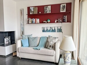 Ein Wohnzimmer mit einer Couch, einem Couchtisch, einer Lampe und einem Bücherregal mit Büchern und Dekoration.