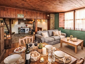 Un salon chaleureux avec un canapé, une table à manger dressée pour le repas, et une cuisine en arrière-plan.