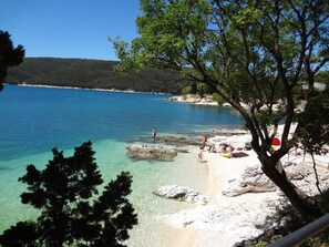 A beach with clear turquoise water, rocky shore, and trees. - Haus Orange - Familienfreundliche Lage mit Pool by Interhome (Drenje)