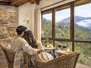 Ein Paar sitzt an einem Fenster mit Blick auf eine gebirgige Landschaft.