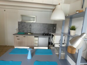 Een koelkast, een microgolfoven, kookgerei, borden en bestek