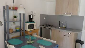 Een koelkast, een microgolfoven, kookgerei, borden en bestek