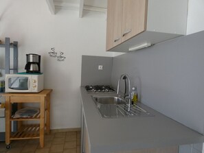 Een koelkast, een microgolfoven, kookgerei, borden en bestek