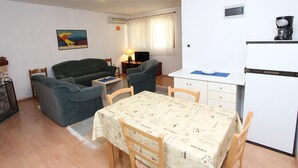 A compact living space with a dining table, two sofas, a TV, and a kitchen area. - Nette Ferienwohnung in Rovinj mit Offenem Kamin by Interhome (Rovinj)