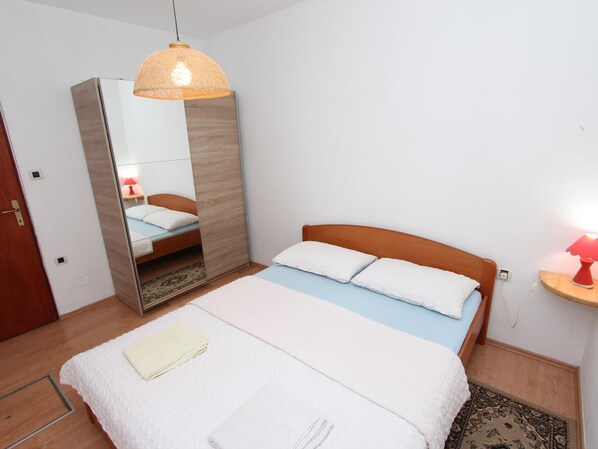 A bedroom with a bed, a bedside lamp, a mirror, and a wardrobe. - Nette Ferienwohnung in Rovinj mit Offenem Kamin by Interhome (Rovinj)