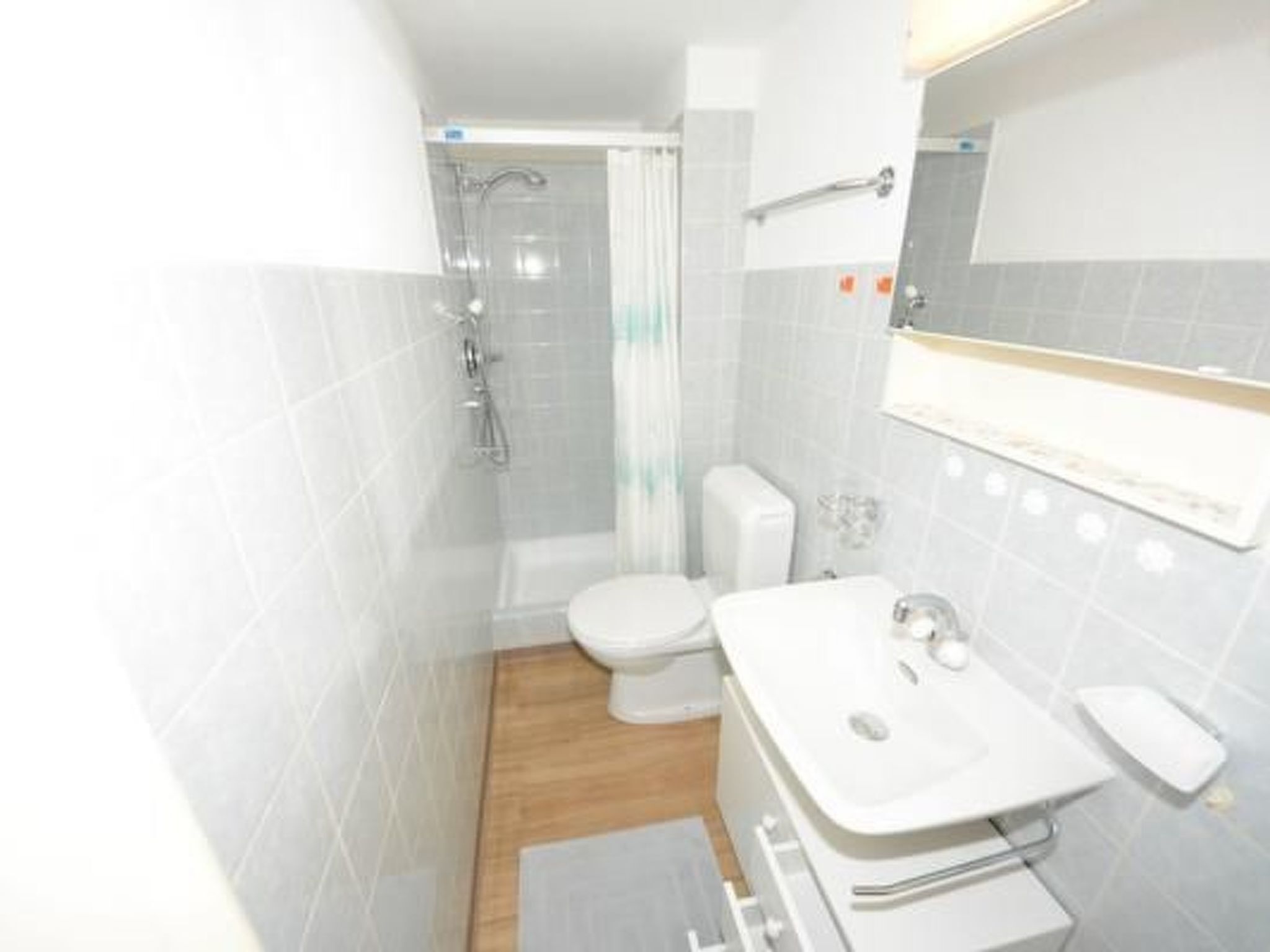 A compact bathroom with a shower, toilet, and sink.