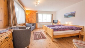Una habitación acogedora con una cama de madera, un sofá, una silla y un escritorio con una lámpara.