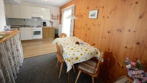 Una cocina acogedora con armarios de madera, una mesa de comedor con mantel floral y una pared de madera.