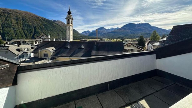 Eine Dachterrasse mit Blick auf eine Stadt und Berge.