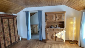 Ein Zimmer mit Holzboden, einem Schrank mit dekorativen Mustern, einer Treppe und einer Lampe.