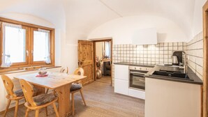 A cozy kitchen with wooden furniture, a dining table, and a view of the adjacent dining area. - Chesa Treig by Interhome (Samedan)