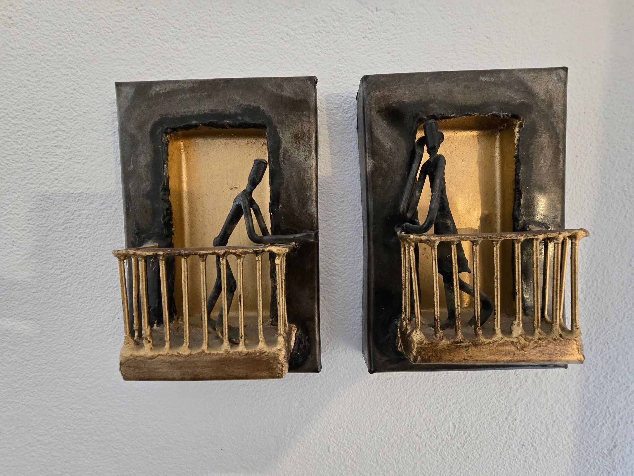 Två väggmonterade skulpturer som föreställer en person som klättrar på en stege.