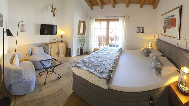 Quarto com cama, cadeira, escrivaninha, televisão e janela.