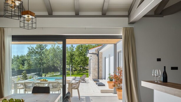 Eine moderne Küche mit Essbereich, großen Fenstern und Blick auf Pool und Garten.