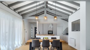 Eine moderne Küche mit Kochinsel, Pendelleuchten und einem Essbereich mit Holztisch und Stühlen.
