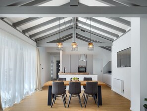A modern kitchen with a central island, pendant lighting, and a dining area with a wooden table and chairs. - Villa Gala by Interhome (Jakovici)