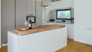 Eine moderne Küche mit einer zentralen Kochinsel, integrierten Geräten und einem Fenster, das für natürliches Licht sorgt.