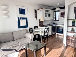 A modern kitchen with white cabinets, a dining area with a glass table, and a living room with a sofa and chairs. - Schöne Wohnung in Playa Blanca mit Grill, Garten und Terrasse und Neben dem Str by Interhome (Playa Blanca)