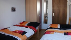Quarto com duas camas, um guarda-roupa, um espelho e uma porta.