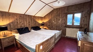 Een slaapkamer met een houten bed, nachtkastjes, een raam en een radiator.