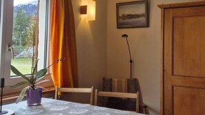 Une pièce comprenant une table, des chaises, une plante en pot, une lampe, un tableau et un meuble en bois.