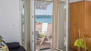A room with a sliding glass door leading to an outdoor seating area with a view of the sea. - Große Wohnung in Klimno mit Möbliertem Balkon by Interhome (Krk/Čižići)
