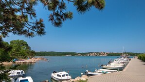 A marina with boats docked along a paved walkway, surrounded by greenery and a clear blue sky. - Große Wohnung in Klimno mit Möbliertem Balkon by Interhome (Krk/Čižići)