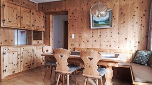 A wooden interior with a dining table, chairs, a bench, and a hanging light fixture. - Chesa Suot Rövens by Interhome (Samedan)