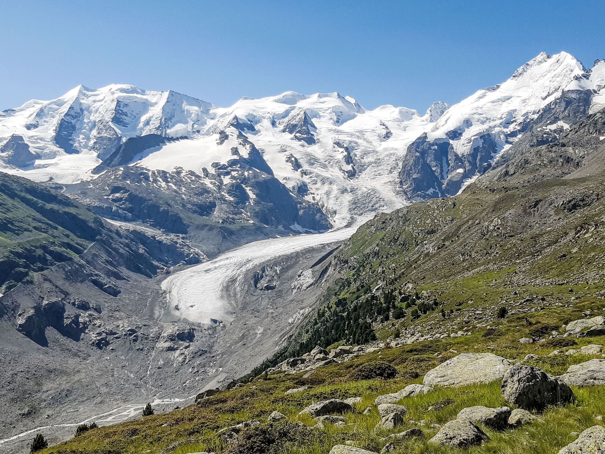 Een bergachtig landschap met een gletsjer en besneeuwde toppen.