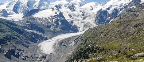 Een bergachtig landschap met een gletsjer en besneeuwde toppen.