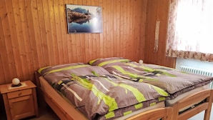 A wooden bed with a patterned bedspread, a nightstand with a spherical object, and a wall-mounted picture. - Chesa Suot Rövens by Interhome (Samedan)