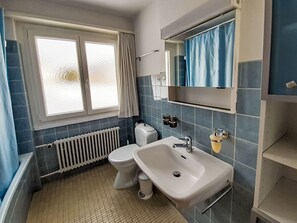 A bathroom with a toilet, sink, and window. - Chesa Suot Rövens by Interhome (Samedan)