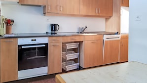 A kitchen with wooden cabinets, a stove, a sink, and a clock on the wall. - Chesa Suot Rövens by Interhome (Samedan)